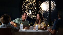 Guests dine by a window as fireworks light up the sky