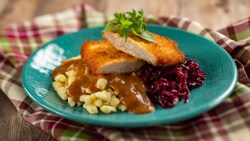 Un plato de schnitzel de cerdo con spätzle y repollo estofado