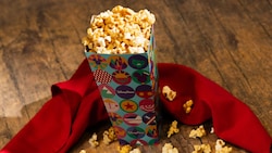 A bucket of maple flavored popcorn is garnished with an elegant cloth napkin