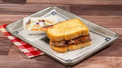 A barbeque sandwich served with coleslaw on a tray 