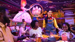 A server approaches a table where a family is eating a meal