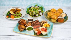 A table featuring grilled chicken, steak, fish, pork, veggies and rice with plantains, salad and dinner rolls from Sebastian's Bistro