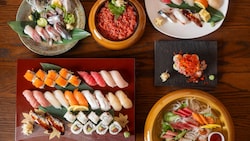 Several plates and bowls holding sushi and other dishes