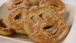 Soft pretzels in the shape of the head of Mickey Mouse, with salt sprinkled on them, on a plate