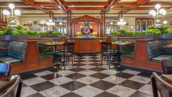 The charming interior of Tony’s Town Square Restaurant at Magic Kingdom park, with tables and chairs, ceiling fans and hanging plants