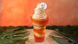 Soft serve ice cream swirled with orange soda in a cup with decorative topper featuring Rafiki