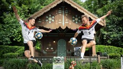 Two men leaping in the air while juggling soccer balls at the Germany Gazebo in Epcot