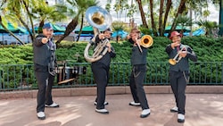 The HollyGroove Swinging Band posing with their instruments in front of lush greenery at Disney’s Hollywood Studios