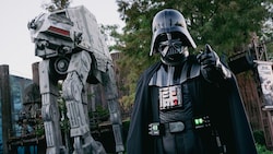 Darth Vader posing in front of an Imperial walker near the entrance to the Star Tours The Adventures Continue attraction in Disney’s Hollywood Studios