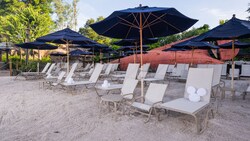 Rows of lounge chairs with rolled towels beneath umbrellas on a beach at Disney's Typhoon Lagoon