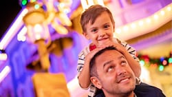 A child sitting on his father’s shoulders at Main Street U S A in Magic Kingdom park