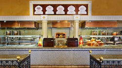 A large restaurant counter with patterned tiles, menu boards above and a wood fired oven