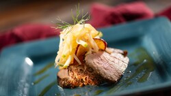 Un plato de solomillo de cerdo asado, cubierto con ensalada de repollo de hinojo y manzana, y una gastrique de sidra de manzana