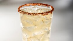 A glass of Pineapple Chipotle Lemonade with tajin on the rim