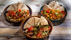 An assortment of hummus bowls topped with vegetables and pita bread at Tangierine Cafe