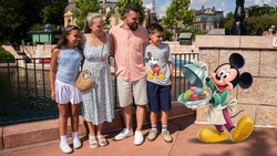 A family of 4 smiling at Epcot near an illustrated overlay of Mickey Mouse holding a tray of macaroons