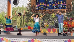 Mirabel Madrigal and Bruno Madrigal perform onstage with singers at the Celebración Encanto stage show