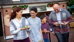 A mom, a dad and their 2 sons share small plates filled with tempting sweets and fruity holiday treats