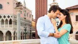 A smiling couple embrace and look into each other’s eyes on a balcony in the Epcot World Showcase Italy Pavilion at Walt Disney World Resort