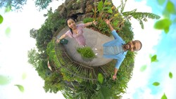 Two people stand with arms outstretched near the Tree of Life