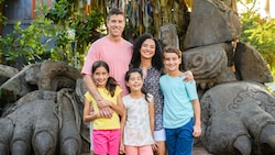 A mom, dad and their 3 kids smile in front of large ruins