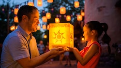 A man and his daughter hold a Rapunzel lantern in Fantasyland