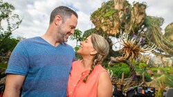 A man and a woman look into each other’s eyes in front of the floating mountains at Pandora The World of Avatar