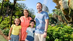 A family of 4 pose for a picture in front of a waterfall at Pandora The World of Avatar