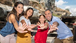 A family hold out their hands in front of the Millennium Falcon