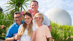 A family of 4 standing in front of Spaceship Earth at Epcot
