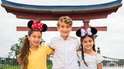 Two little girls in Minnie Mouse ears and a boy smile for a photo in the Japan Pavilion 