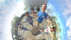 People standing in a circle touching hands in front of the Spaceship Earth attraction at Epcot