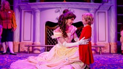Belle from Beauty and the Beast greets a young girl in front of a fireplace