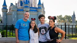 A family of 4 posing in front of Cinderella Castle at Magic Kingdom park