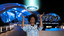 A Guests poses for a photo in front of Tron Lightcycle Run in Magic Kingdom park