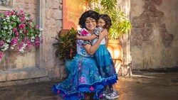 A girl dressed like Mirabel hugging the Character Mirabel 