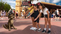 A Disney Magic Shot at the Pirates of the Caribbean attraction at Walt Disney World Resort, with 3 young girls offering the dog from the attraction a bone to tempt it to drop the keys in its mouth