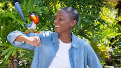 A Guest standing with an animated Zazu perched on her outstretched arm