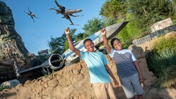 Two kids raise their fists in the air as images of x wings fly above them