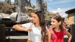 A Disney Magic Shot, featuring a Porg creature from the Star Wars films resting on a girl’s arm as she stands next to another girl, at Star Wars Galaxy’s Edge
