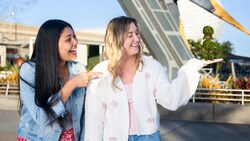 Two Guests posing with a Disney Photopass Magic Shot overlay of Baby Groot as a topiary in the palm of one of their hands
