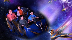 4 Guests in a Guardians of the Galaxy Cosmic Rewind ride vehicle, superimposed on artwork depicting spaceships flying across a galaxy