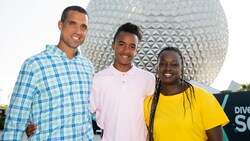 Three people smile for the camera near Spaceship Earth
