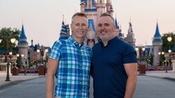 Two men smile for the camera near Cinderella Castle