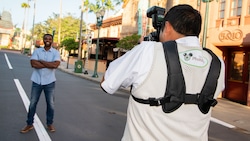A Disney PhotoPass photographer takes a picture of a man outside of the 5 and Dime on Hollywood Boulevard