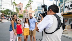 A Disney PhotoPass photographer takes a picture of a family on Sunset Boulevard