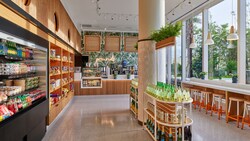 A cafe offering a bar with stools that sells sodas, salads, yogurt and more