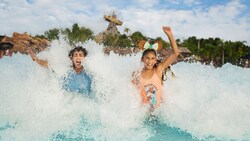 Dos niños disfrutan de un chapuzón alegre en las aguas espumosas de la piscina de surf de Typhoon Lagoon