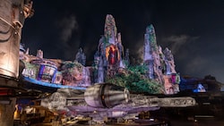 The Millennium Falcon in front of the spires of Batuu in Star Wars Galaxy's Edge at the Disneyland Resort at nighttime