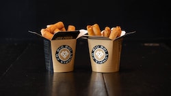 Two containers printed with Big Boi Lumpia Co filled with Filipino spring rolls